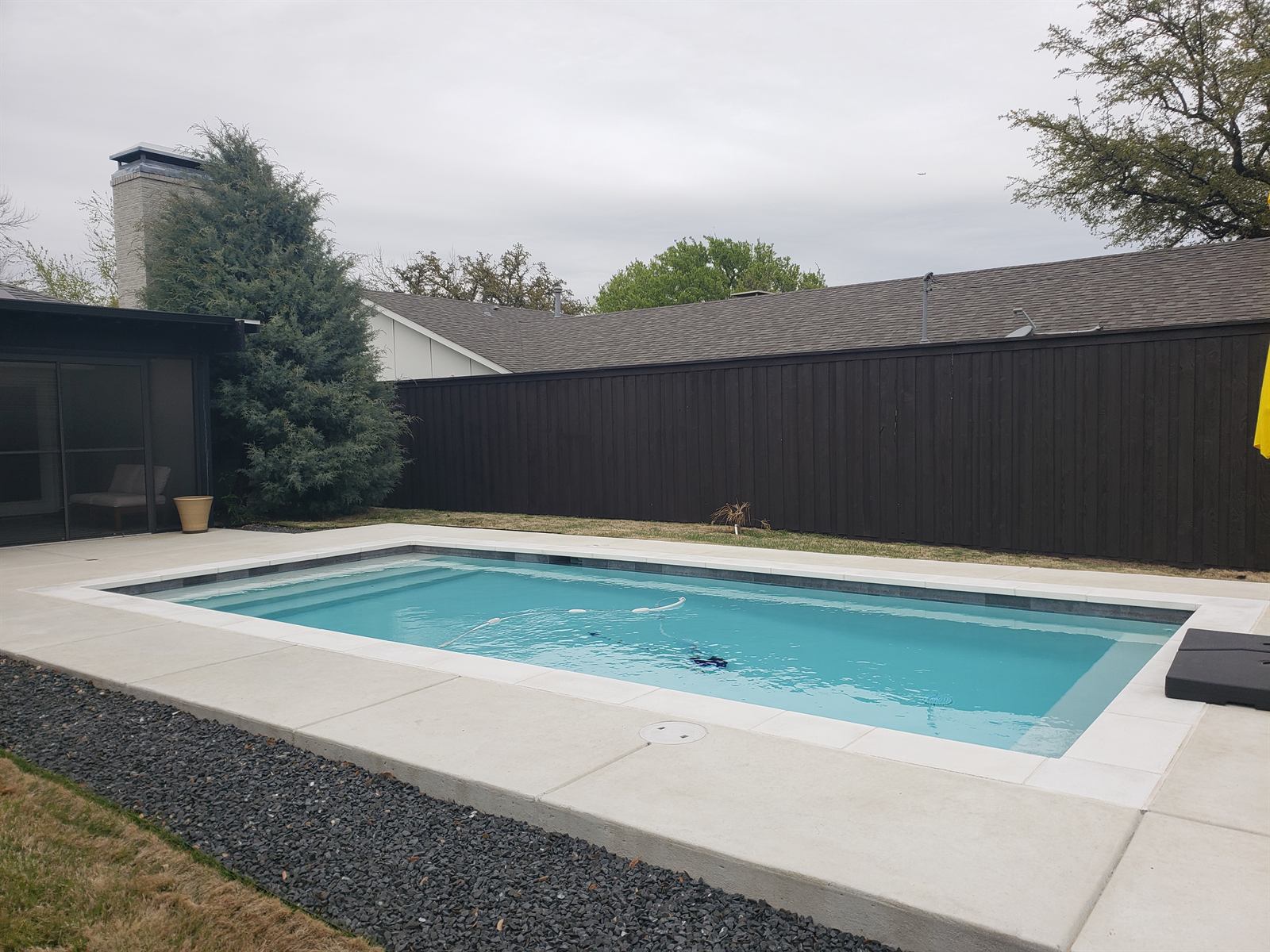 Newly finished black privacy fence enclosing the backyard pool