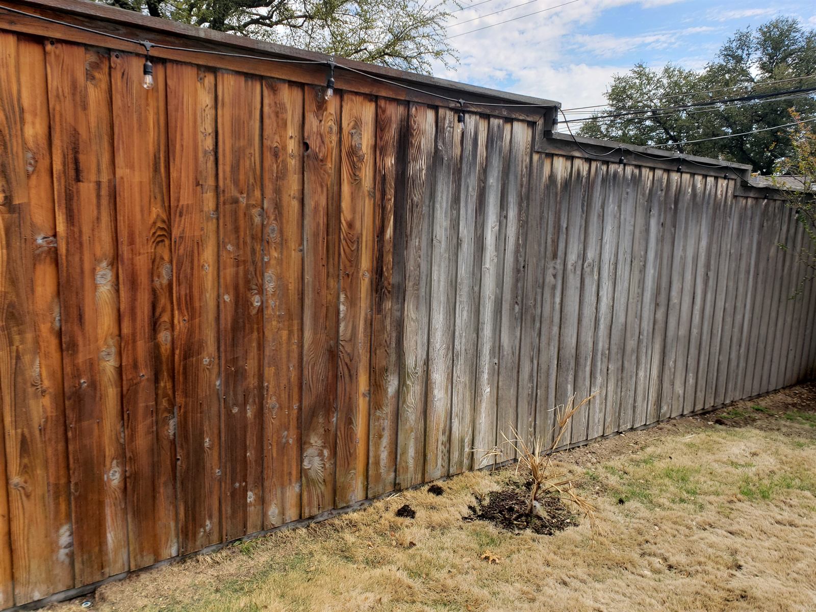 Weathered cedar fence panels with uneven graying and patchy old stain