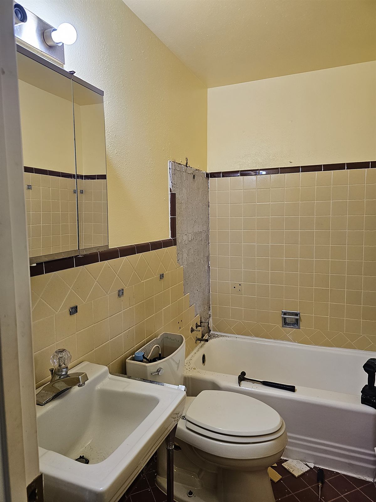 Original bathroom with yellow wall tile, a console sink, and a built-in tub