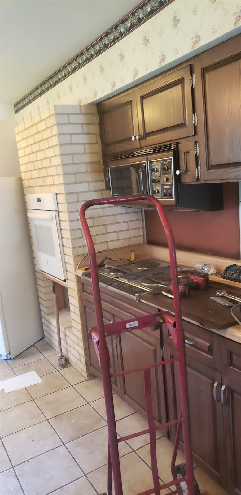 Original kitchen with dark cabinets and tile flooring before renovation